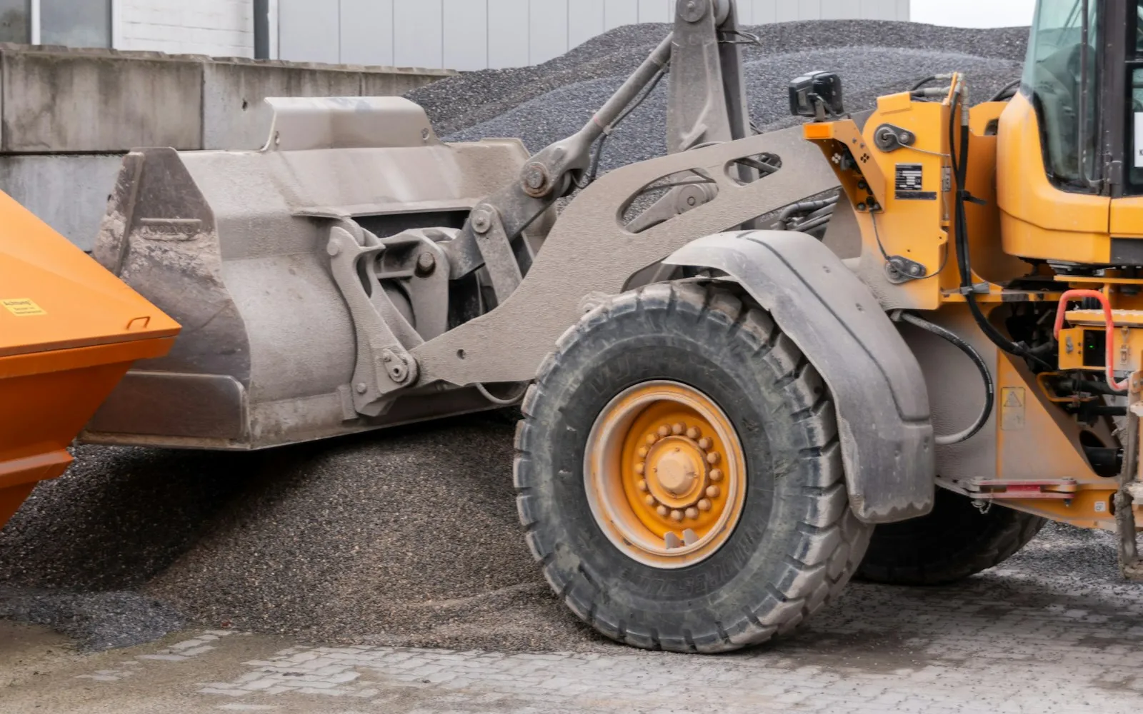 Articulated wheel loader with a full bucket loading gravel into a dump truck